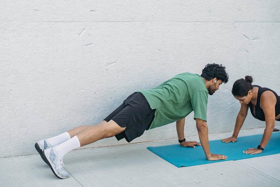 Man and woman practicing plank exercises outdoors on a yoga mat.