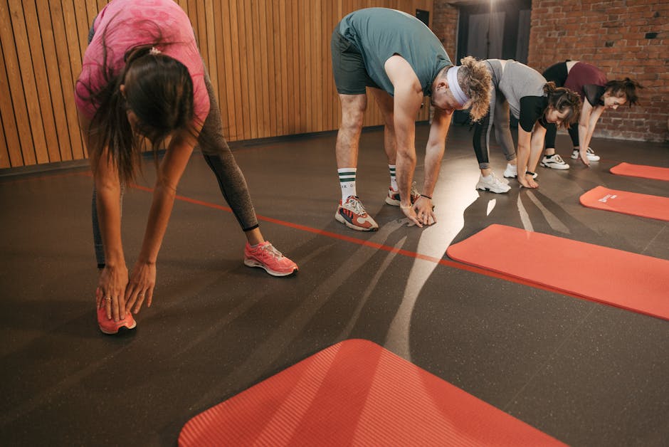 A diverse group of adults stretching on mats during a gym workout session